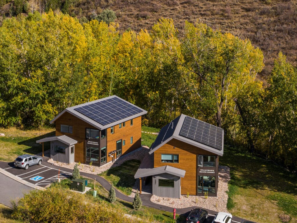 Walking Mountains Educator Housing in Avon, Colorado: two wood-sided homes with rooftop solar panels among fall foliage